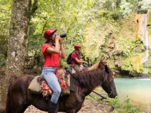 Tourists riding horses through the jungle to reach El Limon Waterfall